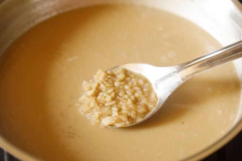 Spoon with rice flakes in pan.