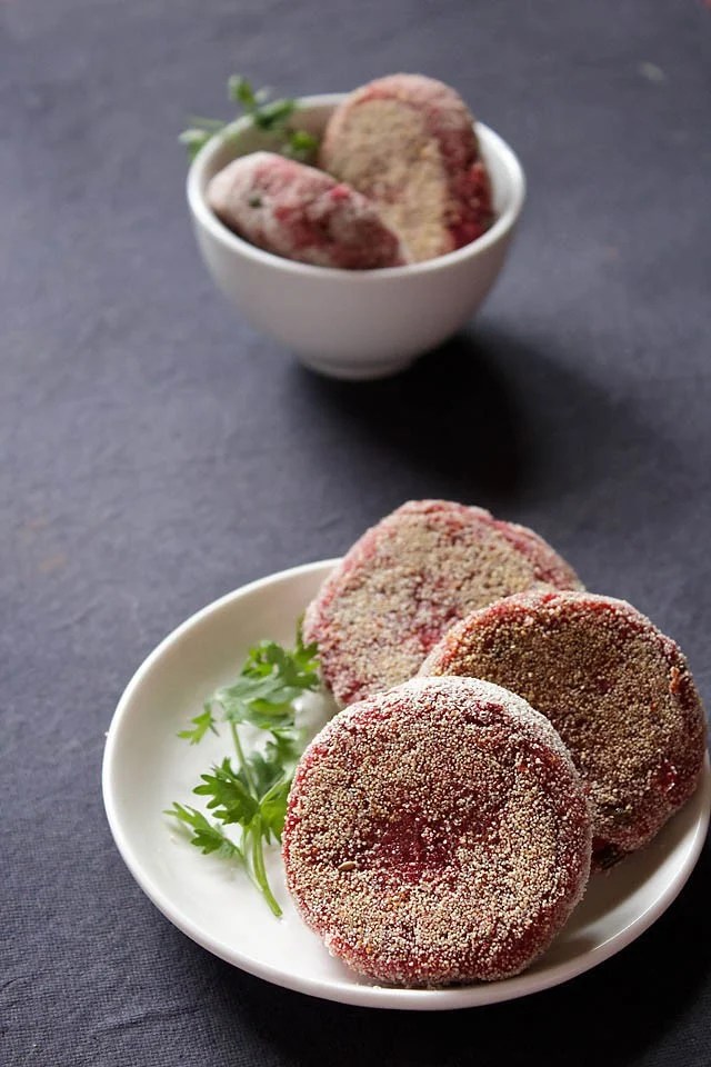 beetroot cutlet served on a white plate with a coriander sprig kept on the side.