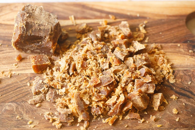 Chopped jaggery on a wooden board.