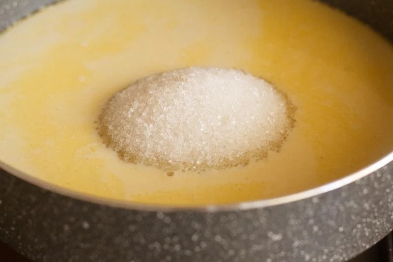 Mound of sugar over melted mawa and milk mixture.