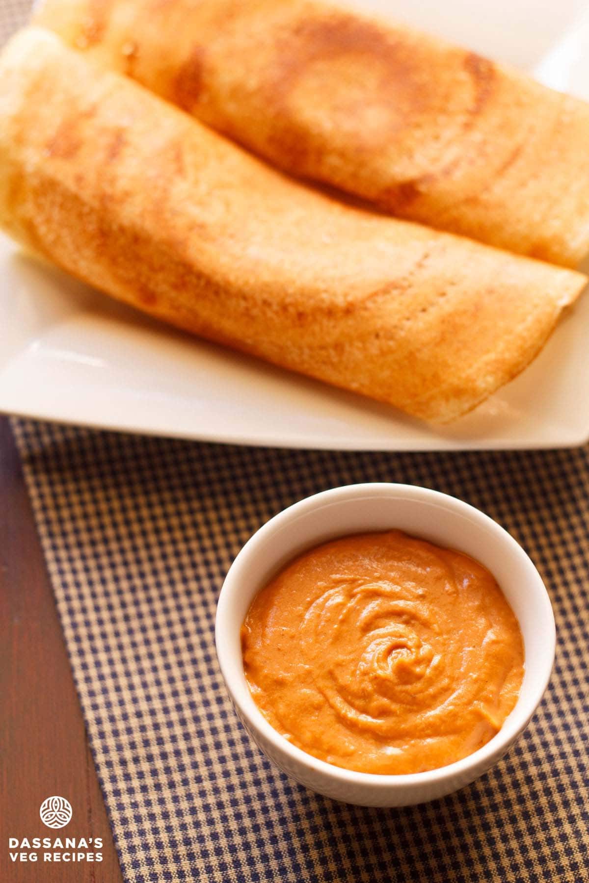 Onion tomato chutney in a white bowl with a crispy dosas.