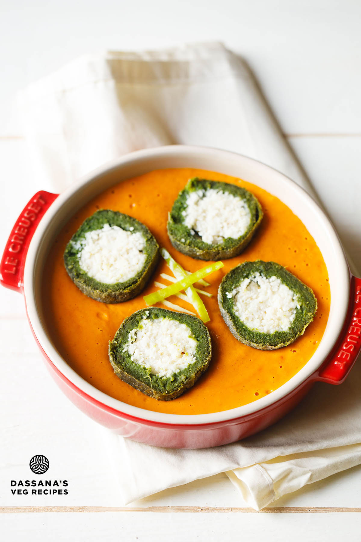 Green and white palak kofta dumplings in orange gravy.