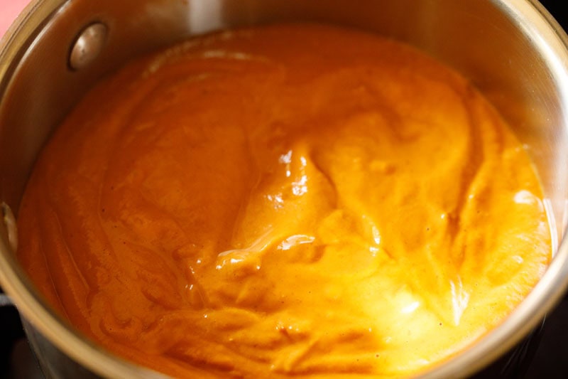 Bright orange colored gravy paste in pan.